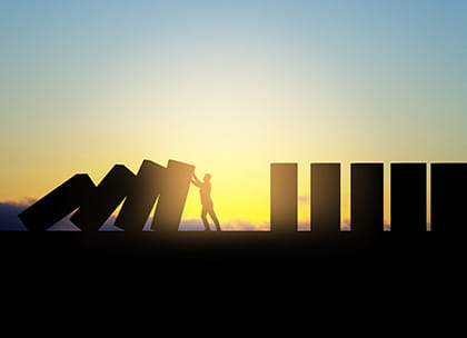 Man silhouetted against the sunset, holding up a line of collapsing pillars